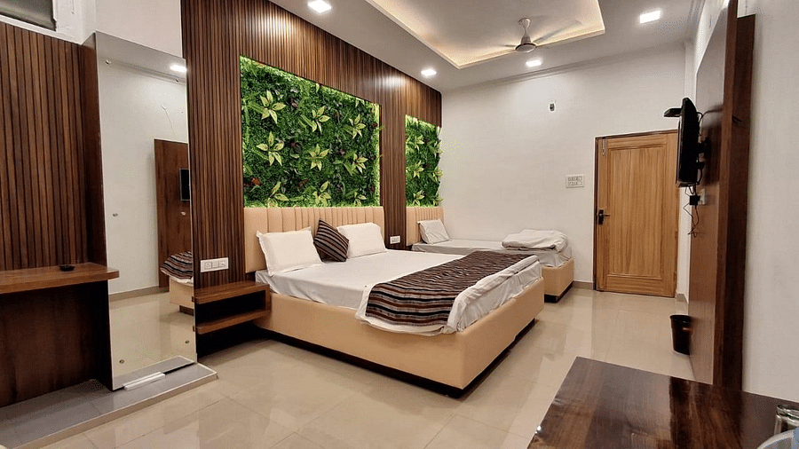 A hotel room in Roorkee with two beds, a wall-mounted television and bright lighting - Motel Divine International, Roorkee