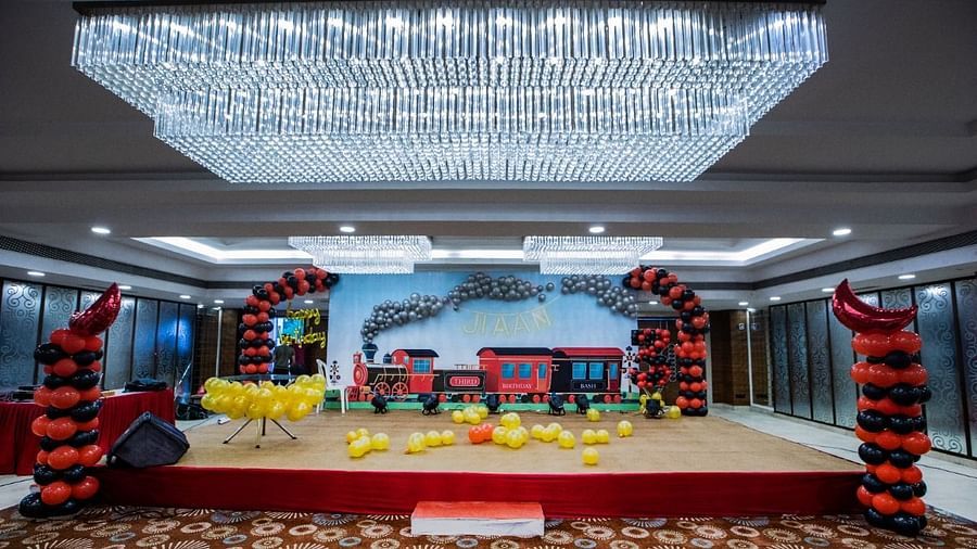 Event hall at Rang Lords Inn with a decorated stage, balloons, and a bright chandelier, set for a celebration
