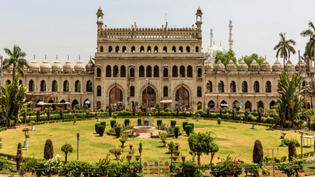 A large, old palace or building with a large green lawn in front.