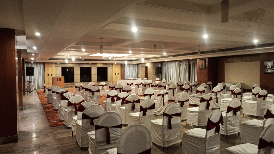A well-lit banquet hall of Lords Plaza Ankleshwar with theatre style seating and elegant interiors creating a warm ambience