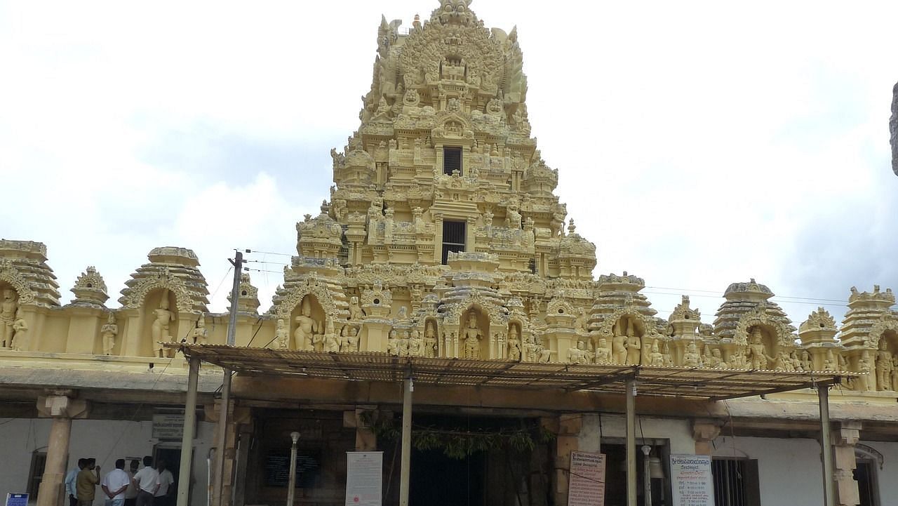 Temple entrance with a golden gopuram and people walking around.