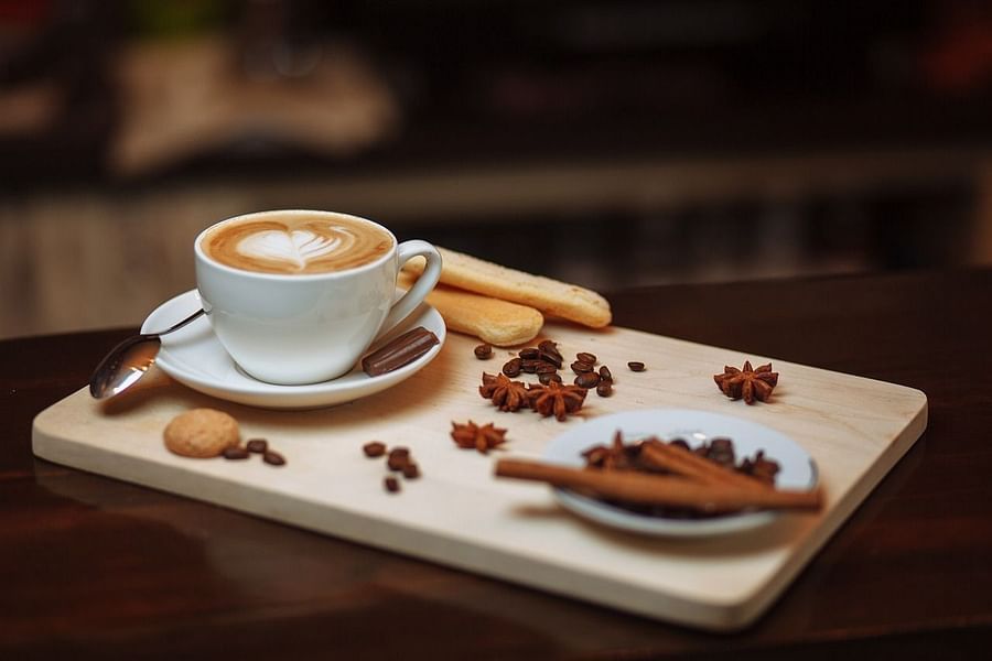 a cup of coffee on a try with coffee beans scattered everywhere