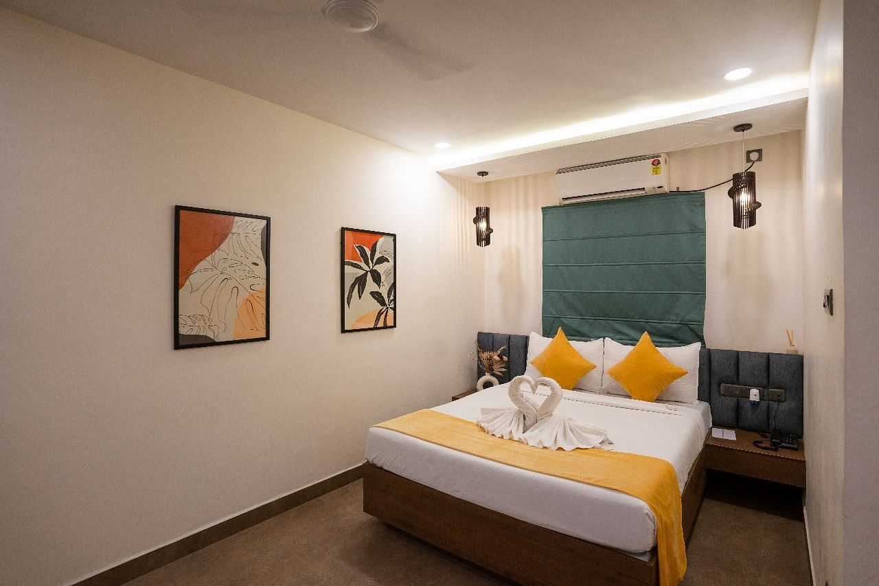 A side view of the room showcasing the bed, warm lighting, wall decor, and a large window offering natural light at Kyzen Smart Stays.