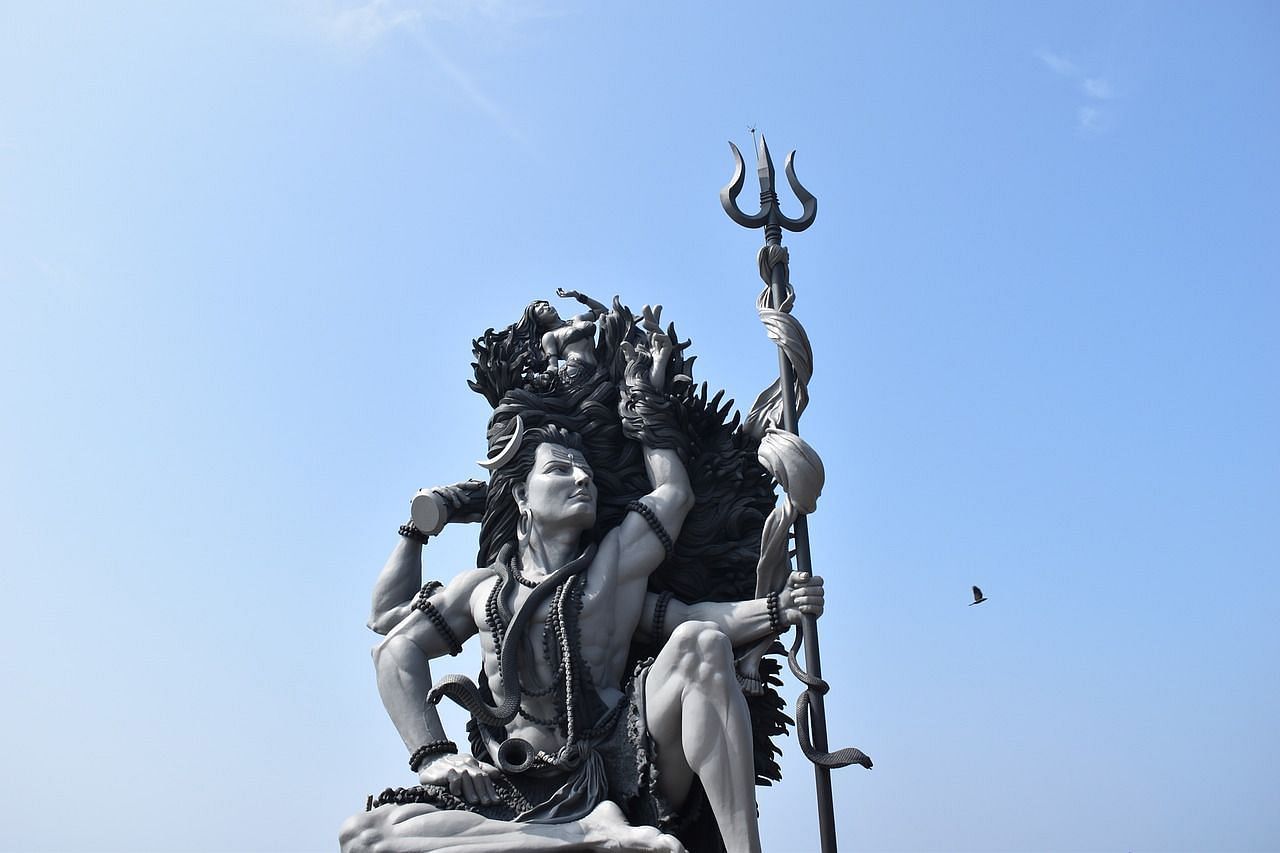 Intricately carved statue of Lord Shiva in a dynamic pose with a trident against a clear sky- Kumarakom