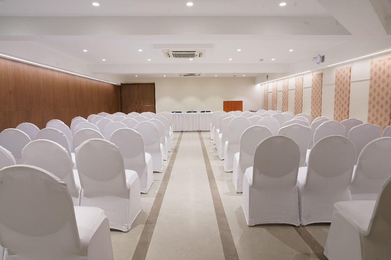 A spacious hall set up with rows of white chairs, ready for a large audience or presentation at Shilton Dee Cee.