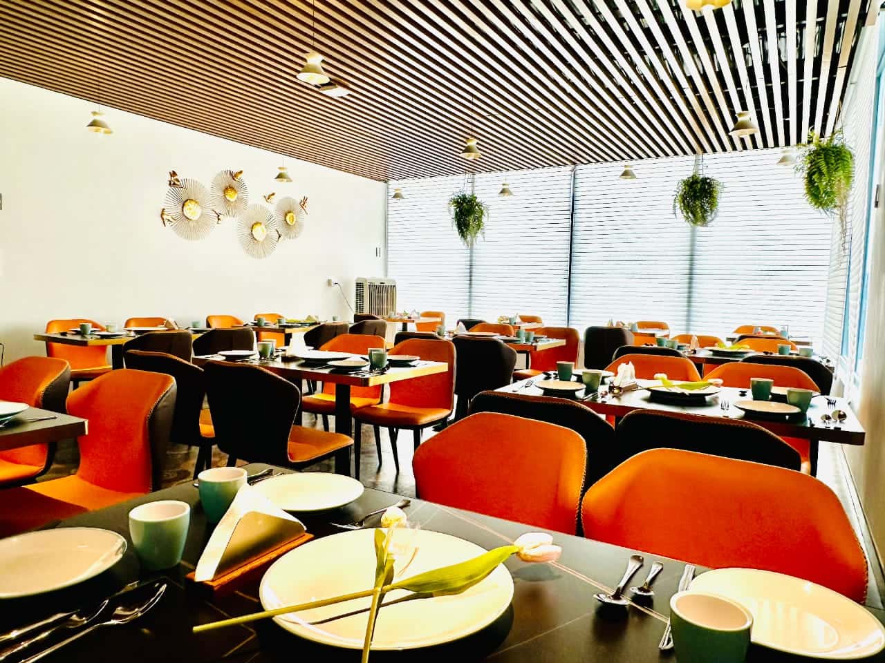 Dining hall with orange chairs, decorative wall discs, and a view toward the lift lobby
