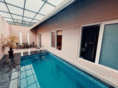 A modern indoor swimming pool features a glass roof and sleek design, offering a bright and airy space. - Abad Brookside Lakkidi, Wayanad