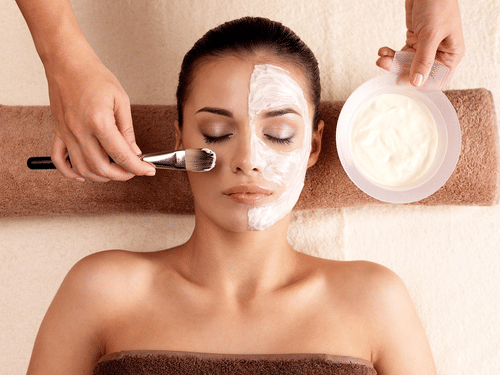 A blissful skincare ritual in progress—half the face adorned with a creamy facial mask, eyes closed in relaxation, capturing the essence of rejuvenation, self-care, and the gentle luxury of spa indulgence.