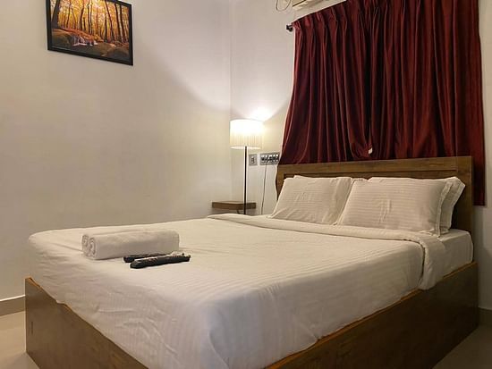 A side view of a bed with bedding in a room with a wall frame and bed lamp