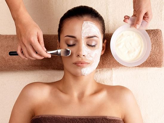 A blissful skincare ritual in progress—half the face adorned with a creamy facial mask, eyes closed in relaxation, capturing the essence of rejuvenation, self-care, and the gentle luxury of spa indulgence.