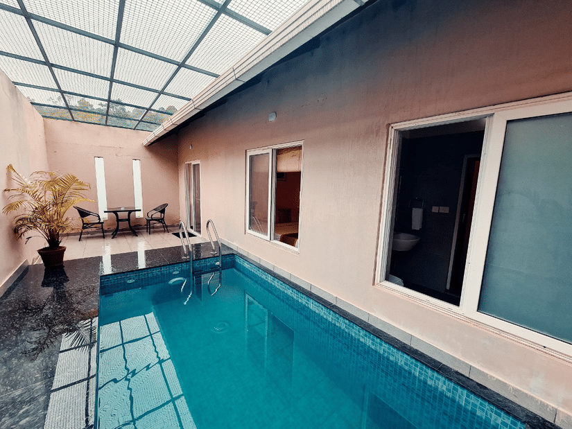 A modern indoor swimming pool features a glass roof and sleek design, offering a bright and airy space. - Abad Brookside Lakkidi, Wayanad