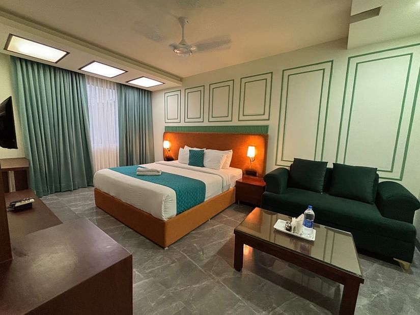 A hotel room featuring a bed, a sofa, a coffee table, and a television - Asian Suites IFFCO Chowk Metro Station, Gurgaon.