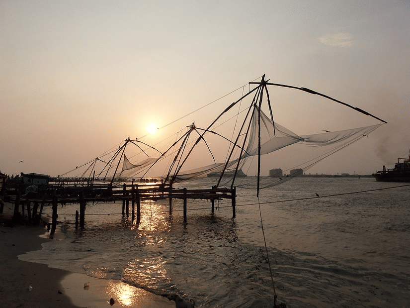 Fort Kochi Beach featuring Chinese fishing nets being used during sunset to catch fish