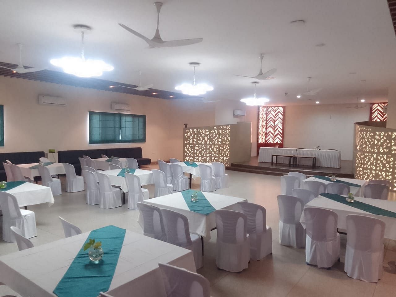A large dining hall with many tables and chairs covered in white cloths - Lords Hotels & Resorts