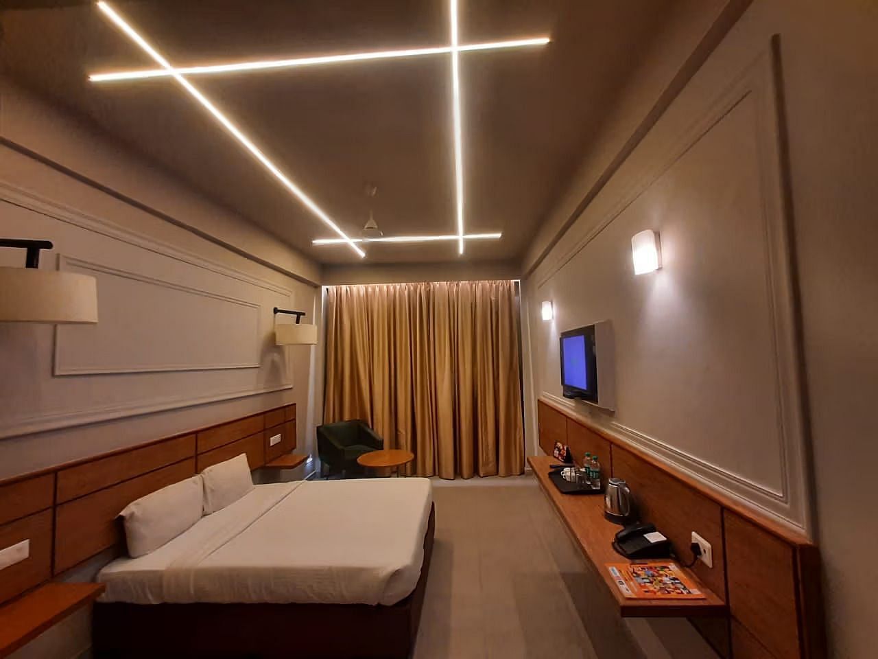 A modern hotel room with a bed, desk, and television.
