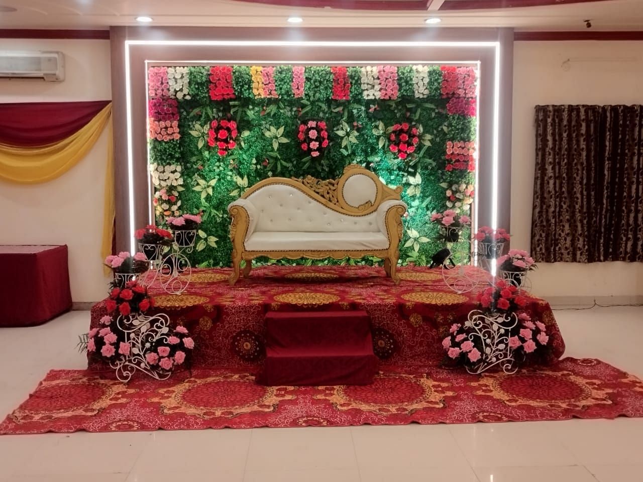 An event hall in Roorkee, elegantly arranged with a chair for the bride and groom adorned with flowers on the walls - Motel Divine International, Roorkee