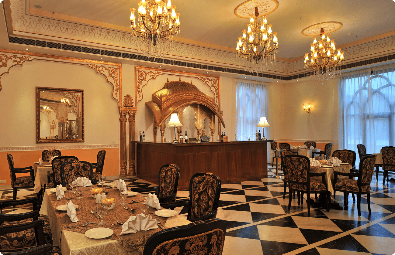 Dining area at Rajasthali Resort & Spa Jaipur with chairs, tables and chandeliers hanging from the ceiling.