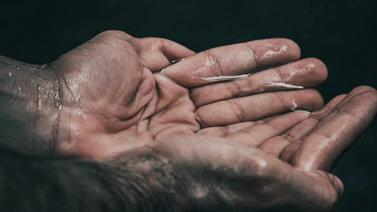 Wet hands cupped together against a dark background.