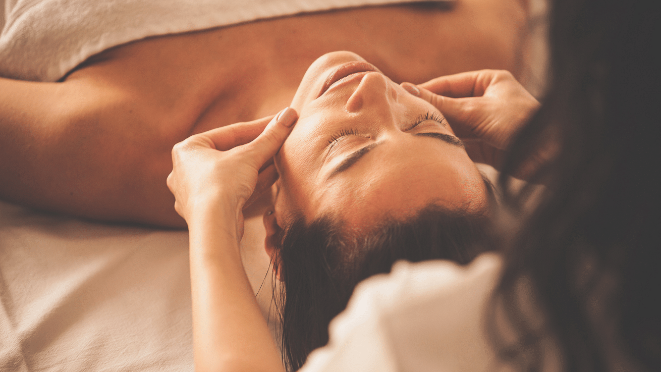 A lady lying on a spa bed taking massage from another  lady