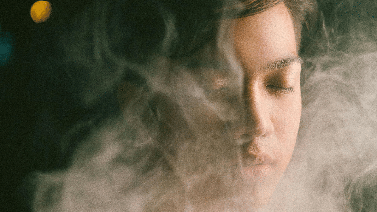 A woman with her eyes closed, surrounded by a cloud of steam.