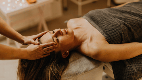 Serene head massage with hands cradling the forehead in a softly lit room.