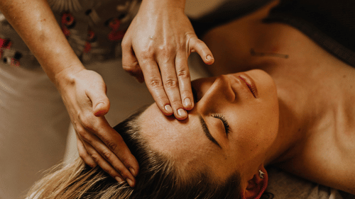 Hands performing a relaxing head massage with a focus on the forehead.