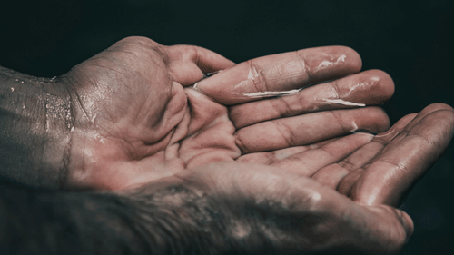 Open palms collecting water, skin detailed and highlighted, conveying the concept of purification or rejuvenation.