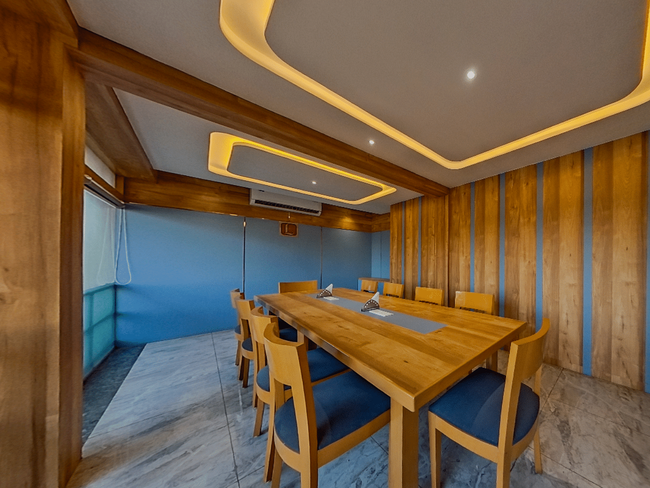 Elegant conference room at Lords Eco Inn Dahej with wooden paneling, blue upholstered chairs, and modern lighting for corporate meetings