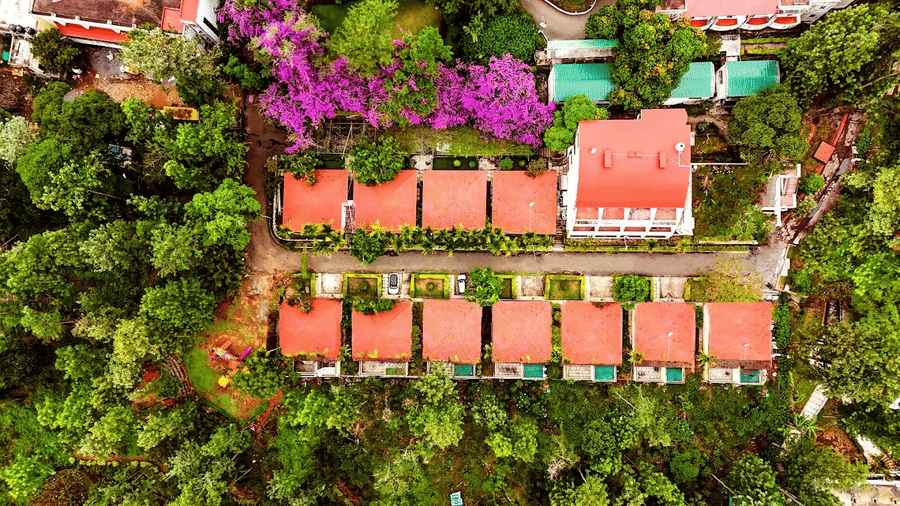 An aerial view shows buildings, pathways, and surrounding trees at DNC Shevaroys Resorts and Spa.