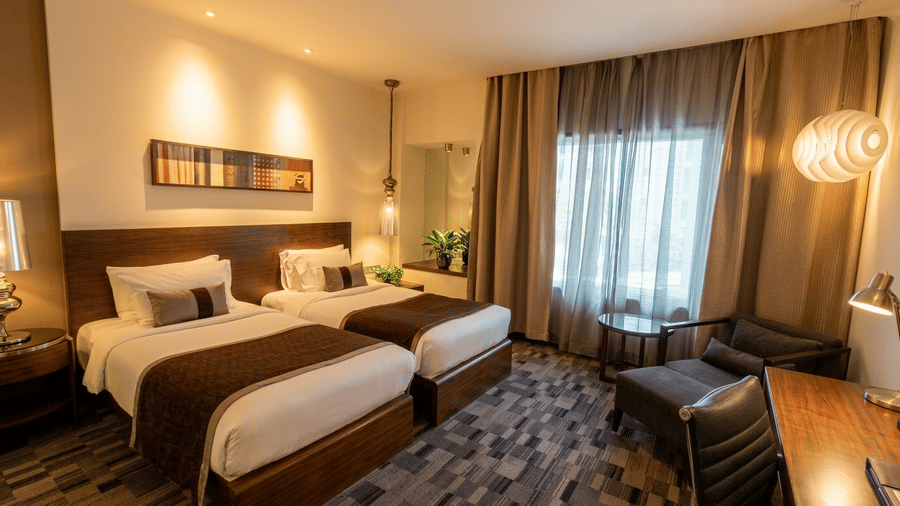 Twin room at Pride Premier Pune featuring two single beds, bedside tables and a seating area by the window.