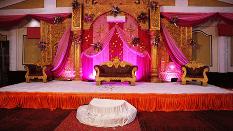 Wedding stage setup at Lime Tree Hotels & Service Apartment Private Limited featuring pink drapes and floral decorations.