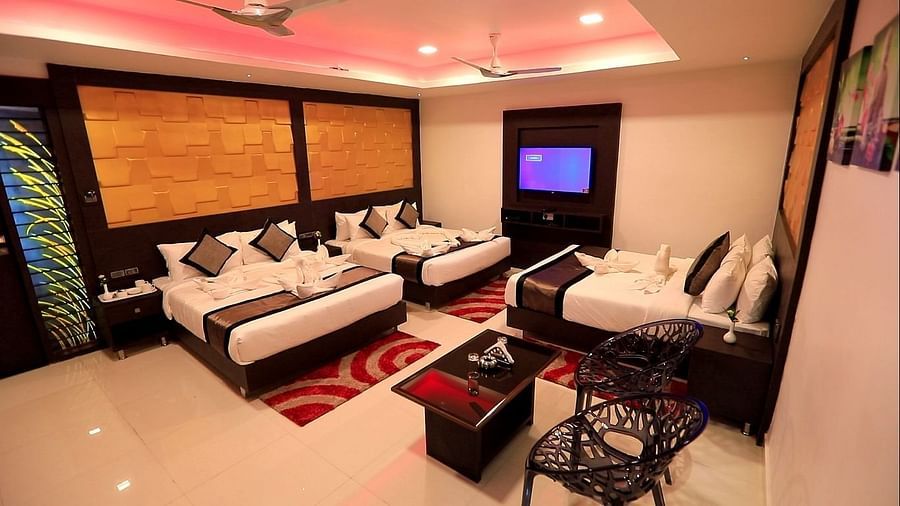 Image of a room with three beds and a sitting area on the side at Parampara Residency, Kushalnagar.