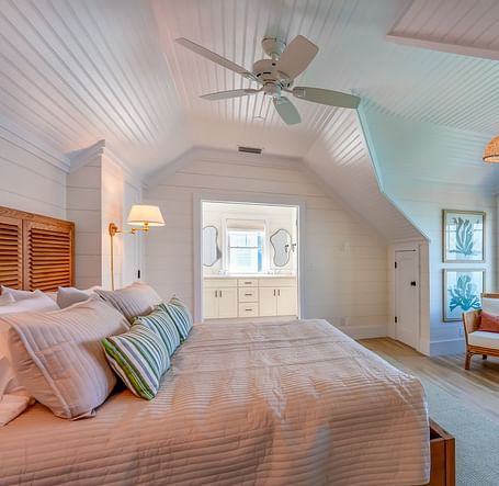 a bedroom at Abaco Inn with a huge bed, wooden floor, chairs, table, ceiling fan and windows overlooking the sea view.