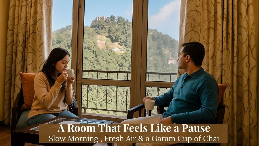 A man and woman seated by a window inside Hotel Shiva Continental, Mussoorie, drinking tea with a clear view of a green forested hillside and distant buildings.