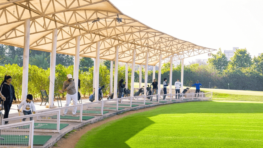 Driving Range at Karma Lakelands with a covered practice area and lush green fairway,  it is accessible with a Delhi Golf Course Membership.