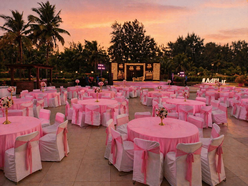 Outdoor lawn event venue decorated with pink tablecloths and draped seating at Kenilworth Resort & Spa, Goa.