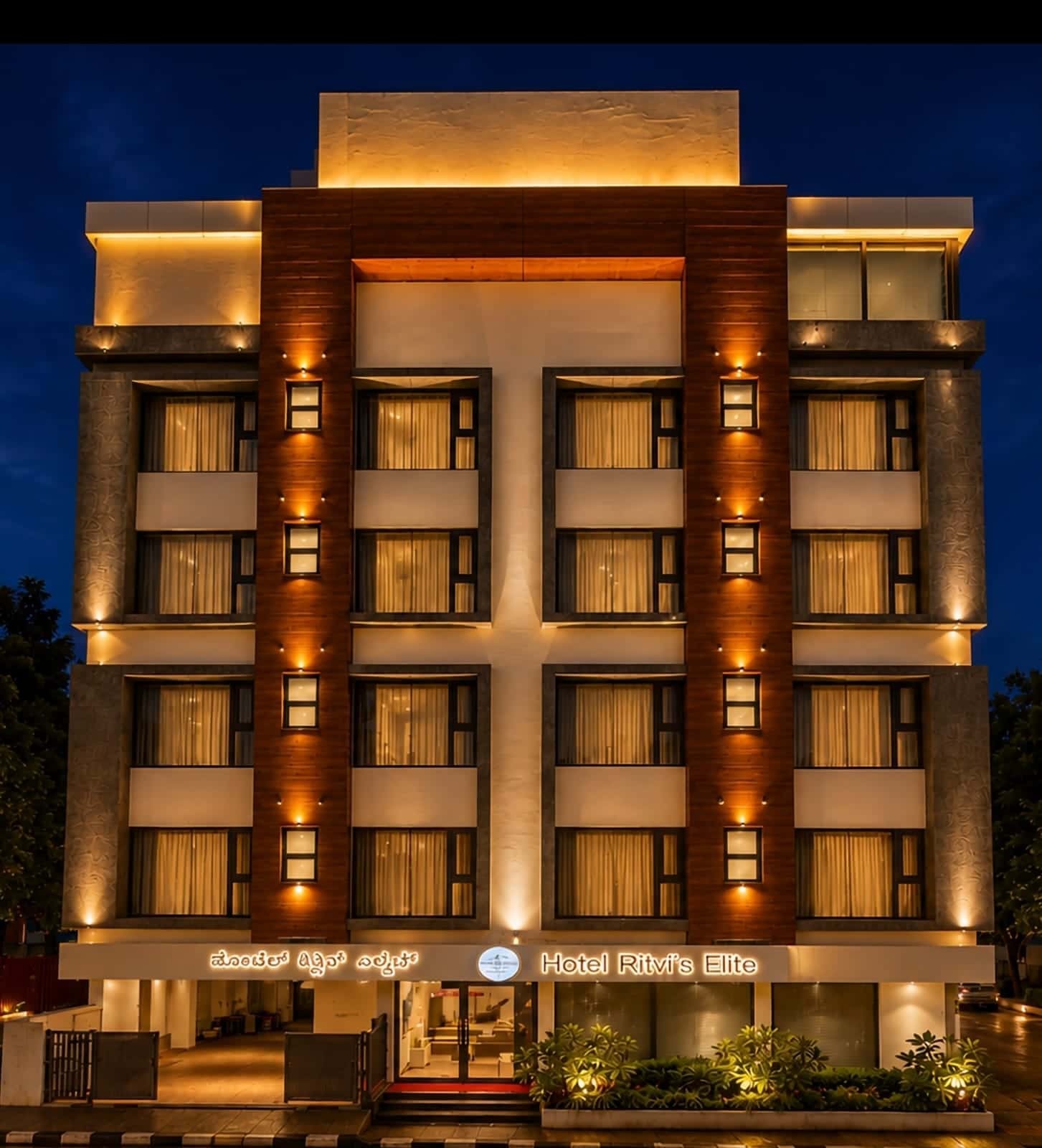 The illuminated frontage of Hotel Ritvi's Elite at dusk, seen from the street