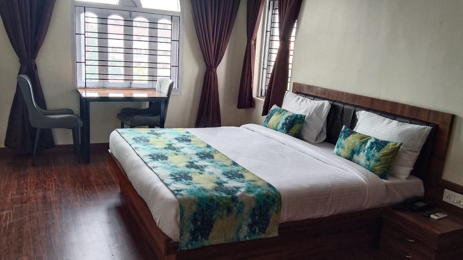 A double bed with chairs & study table next to it inside Premium room with balcony - Ecotel Kolkata