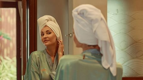 Woman with a towel on her head adjusting her earring in the mirror - Maikhao Dream Villa Resort & Spa, Phuket