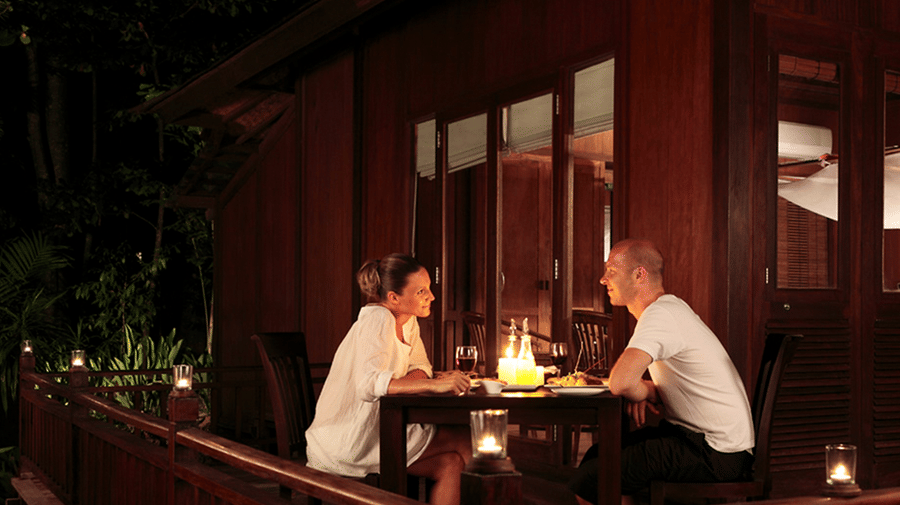 A couple romantically looking at each other and enjoying a meal at the in-house restaurant of Barefoot at Havelock. The resort provides numerous packages in Andaman, including a romance special package.