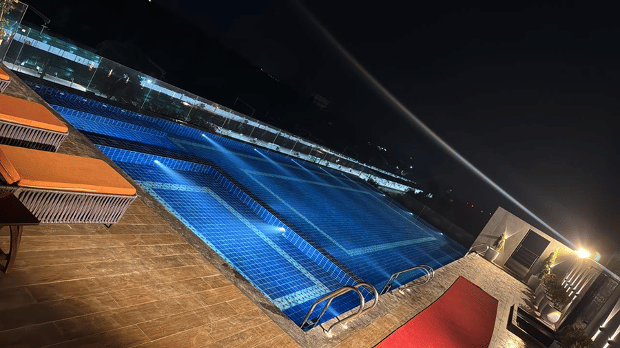Rooftop swimming pool area at Le ROI Digha Hotel, West Bengal, with poolside seating for guests and a deck.