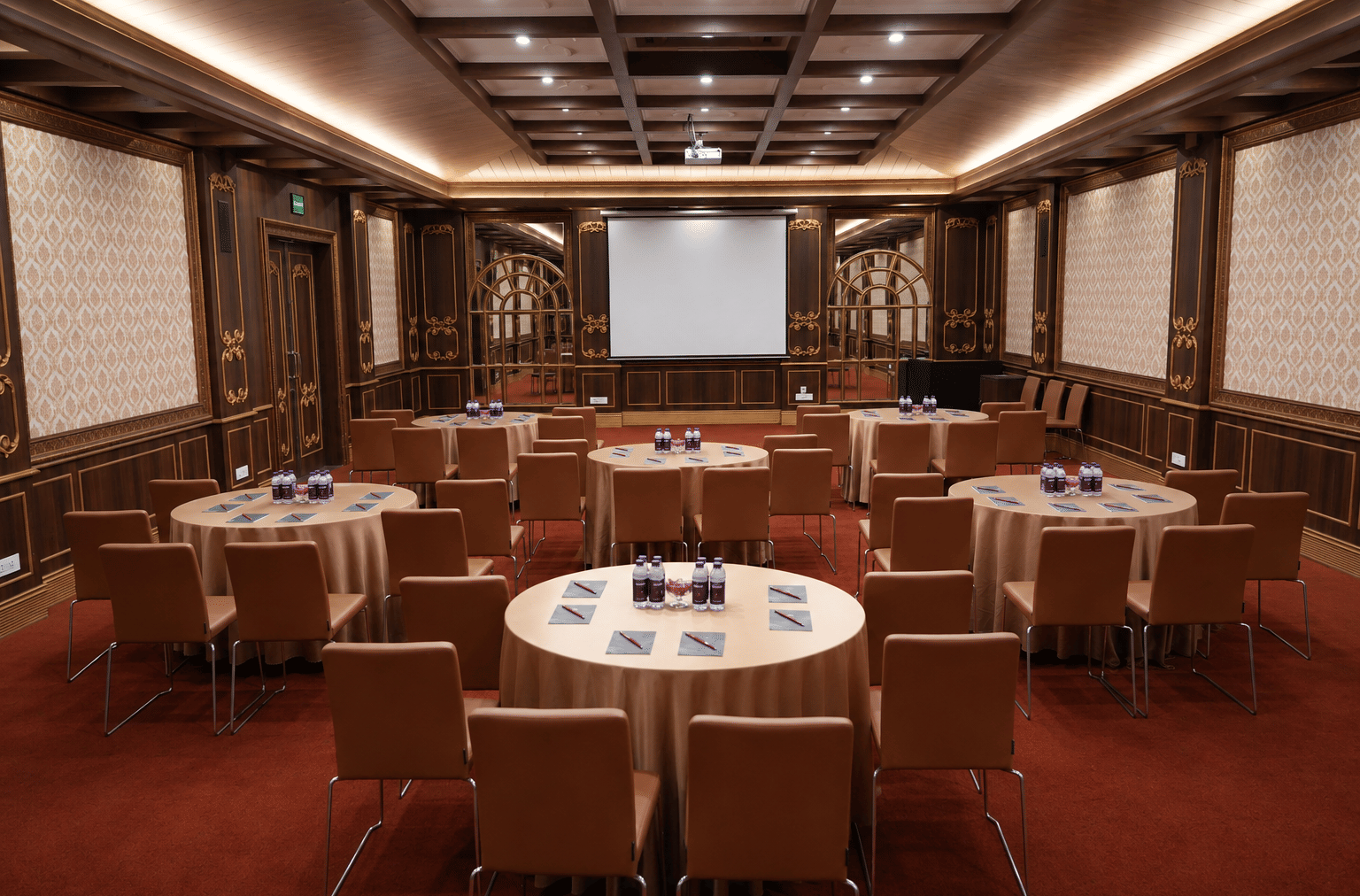 Kanchenjunga Hall arranged with round tables and chairs facing a projector screen, with damask wall panels at MAYFAIR Himalayan Spa Resort, Kalimpong.
