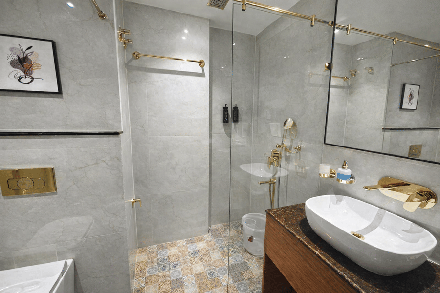 Washroom at Pride Premier Darjeeling featuring sink with faucet, mirror attached on the wall, a shower screen, jet sprays, shower heads, and other bathroom amenities.