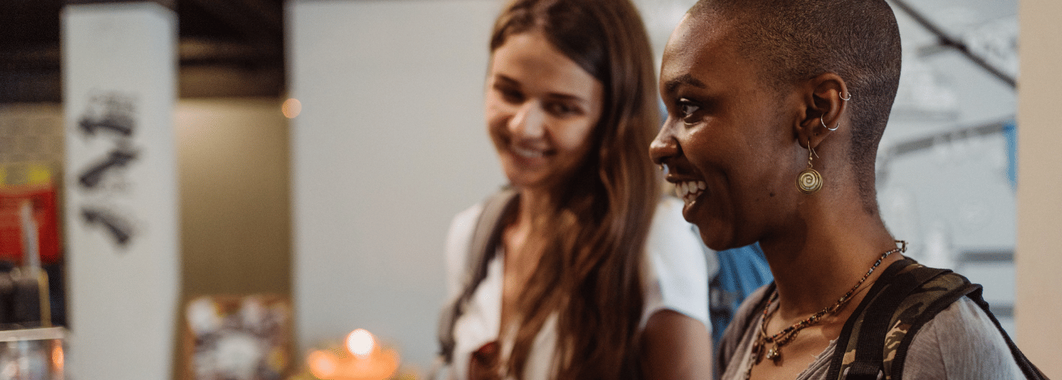 Two women smiling and engaging in a conversation, symbolising a friendly interaction or enjoyable experience.