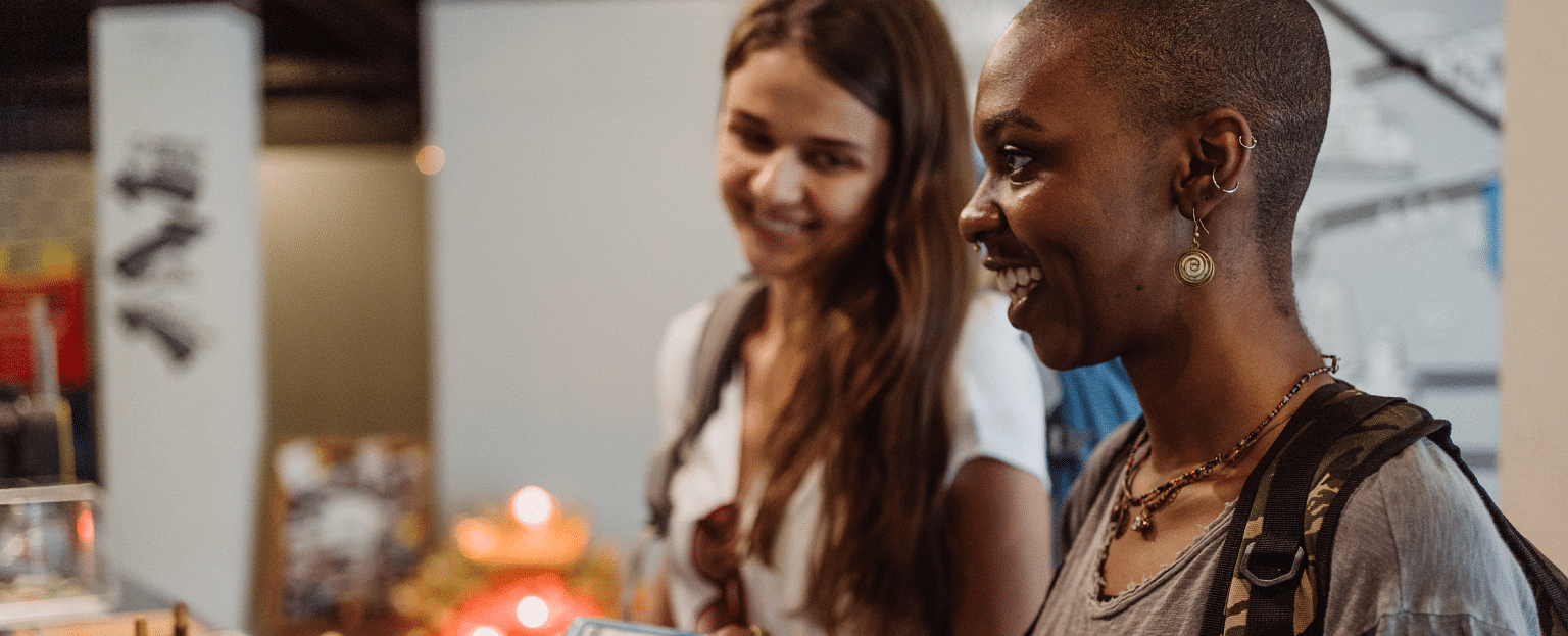 Two women smiling and engaging in a conversation, symbolising a friendly interaction or enjoyable experience.