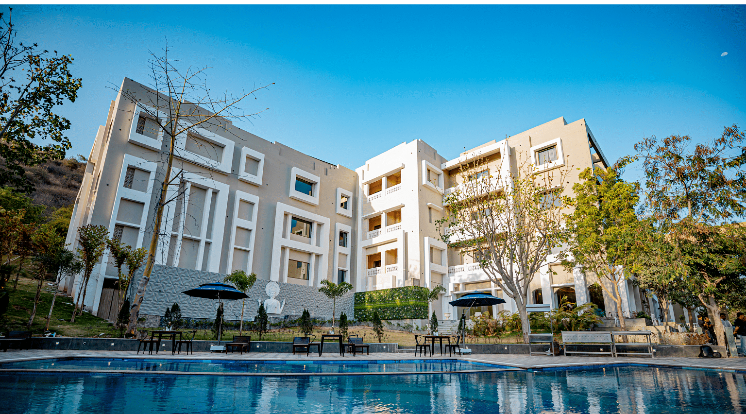 Facade image of Essentia Luxury Resort & Spa, Udaipur with a swimming pool in front of it