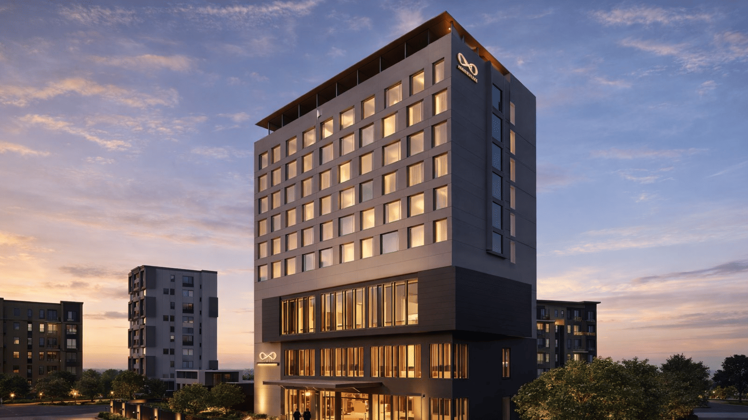 The KPG Sarovar Portico, Raj Nagar Extension, Ghaziabad, building at dusk, featuring many illuminated windows and 2 cars parked near the entrance under a sky with soft clouds.