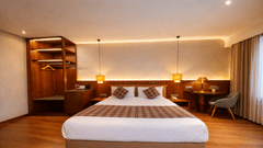 A bedroom with a double bed, a wooden wardrobe with open shelving, and a small desk area | Pride Premier Darjeeling