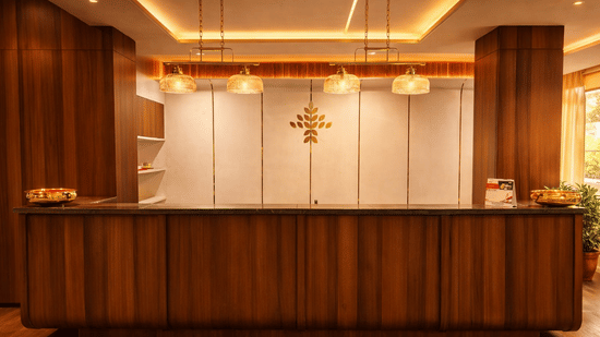 A wooden reception desk at the hotel lobby under warm hanging lights | Pride Premier Darjeeling