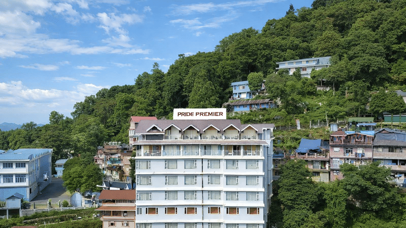 An exterior view of the facade of Pride Premier Darjeeling set on a lush green hillside.
